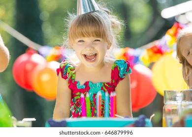 Cô bé vui vẻ thổi nến trên bánh sinh nhật