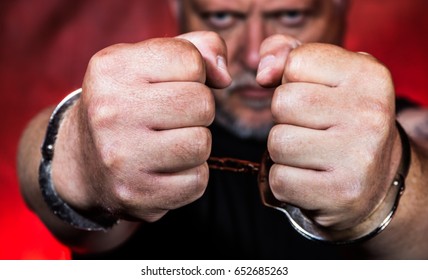 A man in handcuffs against red background