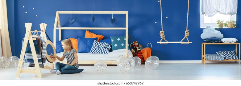 Little girl playing in her room with navy blue wall