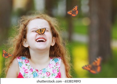Cô gái xoăn cười vui nhộn với một con bướm trên mũi. Nụ cười khỏe mạnh với hàm răng trắng. Khái niệm thở tự do.