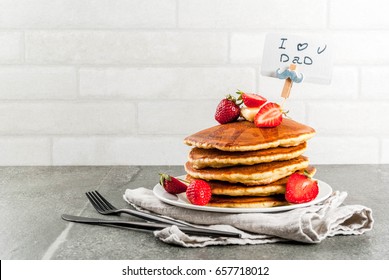 Celebrating Father's Day. Breakfast. The idea for hearty and delicious holiday breakfast: pancakes with butter, maple syrup and fresh strawberries, with congratulations. Coffee cup. Copy space