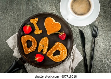 Vatertag feiern. Frühstück. Die Idee für ein herzhaftes und leckeres Frühstück: Pfannkuchen in Form von Glückwünschen - I love dad. In einer Bratpfanne, Kaffeetasse und Erdbeeren. Kopienraum der Draufsicht