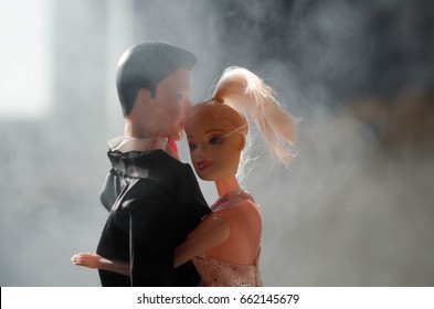 Los novios de muñecas en el interior se abrazan. Chica hermosa modelo en vestido blanco. Hombre de traje Concepto de amor de boda. De cerca, fumar en el fondo. Enfoque selectivo