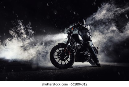 High power motorcycle chopper with man rider at night. Fog with backlights on background.