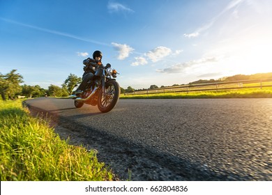 美しい夕日の光で、自然の中で高出力のバイクに乗る暗いモーターバイカー。旅行と輸送。オートバイに乗る自由