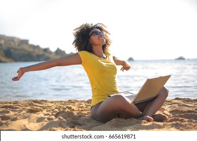 Succesvol meisje dat op het strand werkt en ontspant