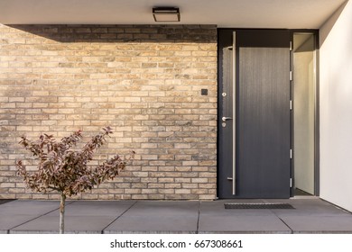 Exterior minimalista limpio de ladrillo rojo con puerta delantera negra