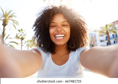 Selfie portrait of laughing black woman outside with curly hair