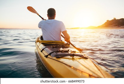 Vista trasera del kayakista de remo en el mar al atardecer. Kayak, canoa, remo