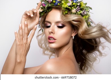 長い巻き毛、完璧なメイク、春の花の花輪を持つ美しい女性