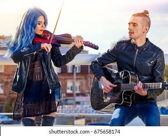 都市公園のフェスティバル ミュージック バンド。男はギターを弾き、愛についての歌を歌い、女の子はヴァイオリンで彼を伴奏します。