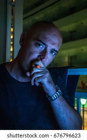 Retrato de um homem de negócios trabalhando no escritório à noite. Homem usando um laptop contemporâneo e fumando um charuto