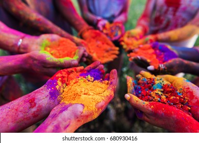 close-up partial view of young people holding colorful powder in hands at holi festival 