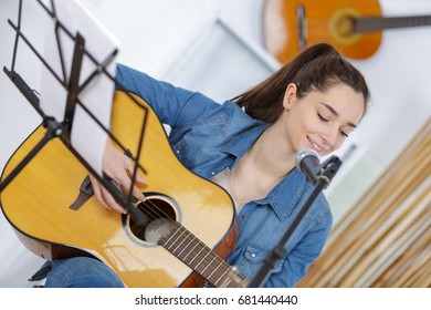 young woman play with guitar at home