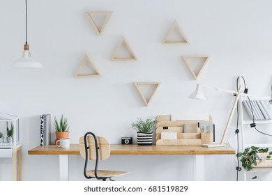 White scandi interior with wooden desk, triangle shelves and plants