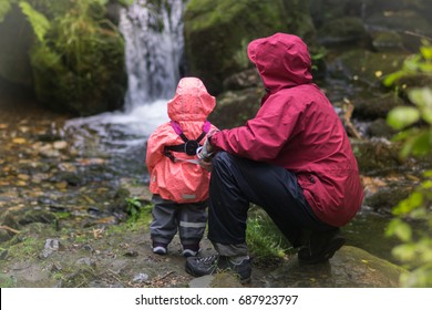 自然への家族旅行: 夏の雨林で滝を見ている父と女の赤ちゃん