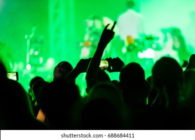 ファンは、ハムレット メタル バンド Rammstein のコンサート中にホールのファン ゾーンでコンサートを楽しんでいます。手を上げた大勢の人々のシルエット。セレクティブ フォーカス
