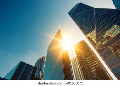 青空に太陽光線が差し込む明るい晴れた日に超高層ビルのガラスのファサード。パリのビジネス地区ラ・デファンスにある近代的な建物。経済、財政、事業活動の概念。ボトムアップ ビュー