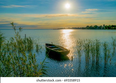 Bote de remos en el lago al atardecer Pequeño bote de remos de madera en un lago tranquilo al atardecer caña