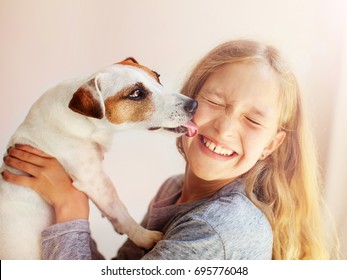 犬と一緒に幸せな子供。ペットを持つ肖像画の女の子。ジャック・ラッセルがティーンを舐める