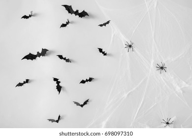 halloween, decoration and scary concept - black flying bats and spiders on web over white background