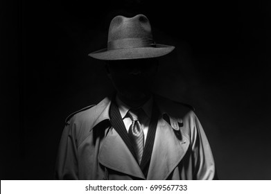 Man die in het donker poseert met een fedora-hoed en een trenchcoat, personage uit de jaren 50 noir-filmstijl