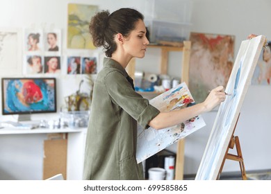 Pintora bastante talentosa pintando en caballete, haciendo bocetos coloridos, creando paisajes marinos. Hermosa artista femenina pintando con pinturas de acuarela. Concepto de creatividad e imaginación.