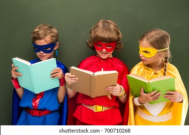 superheronj të vegjël me kostume që lexojnë libra, dërrasë prapa