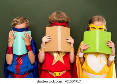 superheronj të vegjël me kostume që mbajnë libra, prapa dërrasë