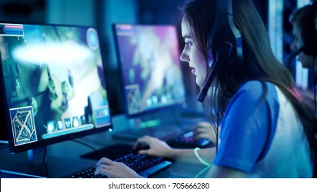 Professionelle Mädchen-Spieler spielen im MMORPG / Strategie-Videospiel auf ihrem Computer. Sie nimmt am Online-Cyber-Games-Turnier teil, spielt zu Hause oder im Internet-Café. Sie trägt ein Gaming-Headset.