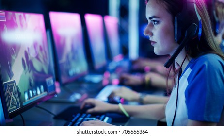 Professionelle Mädchen-Spieler spielen im MMORPG / Strategie-Videospiel auf ihrem Computer. Sie nimmt am Online-Cyber-Games-Turnier teil, spielt zu Hause oder im Internet-Café. Sie trägt Gaming-Kopfhörer.