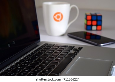 Laptop con taza borrosa, teléfono y cubo de rubik