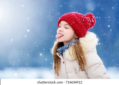 Schattig klein meisje dat sneeuwvlokken vangt met haar tong in een prachtig winterpark. Schattig kind dat in de sneeuw speelt. Winteractiviteiten voor kinderen.