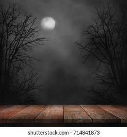Old wood table and silhouette dead tree at night for Halloween background.