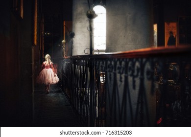 công chúa nhỏ trong một lâu đài cổ.cô bé với mái tóc vàng trong chiếc váy hồng nhạt trong một ngôi nhà bằng đá cũ có ban công.