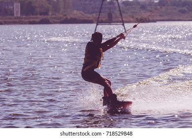 Wake Park. Sporturi nautice de vară pe plajă. Atletul alunecă la bord pe apă. zmeu pe apă. kiteboarding, wakeboarding. Siluetă în lumină de fundal cu procesare originală a designului. Fundal sportiv de vară