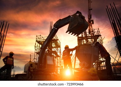 Equipos de ingenieros de negocios en busca de planos en sitios de construcción a través de sitios de construcción borrosos al atardecer.