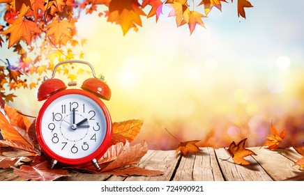 Sommerzeit-Konzept - Uhr und Blätter auf Holztisch