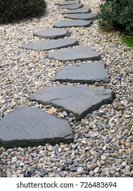 Pad van geplateerde stenen op grindbed in Japanse tuin. Meditatieve stenen loopbrug. Tuinarchitectuur, padaccessoire voor tuinvijver.