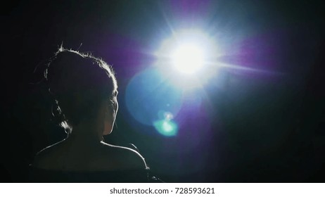 Girl in long gown performing on stage. the girl singing on the stage in front of the spotlight. Silhouette of singer standing on stage at microphone in night club