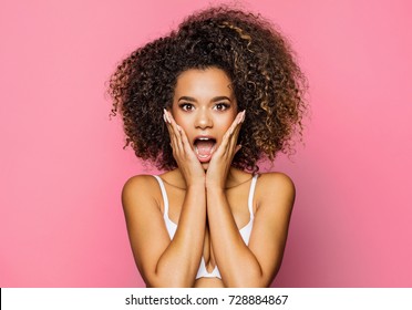 Surprised beautiful black woman holds cheeks by hand
