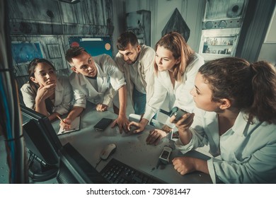 Vijf positieve Italiaanse volwassenen die samen raadsels oplossen in de onderzoeksruimte in het zicht als verlaten lab