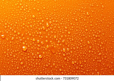オレンジ色の背景テクスチャに水滴がカラフルな水滴