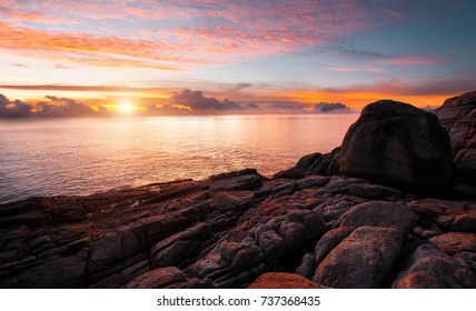 Kust zee. Zonsondergang. Wild rotsstrand. De natuurlijke rotsformatie. Rode zon over de zomerzee. Wolk op een blauwe lucht boven de zomerzee. Bergen in Thailand