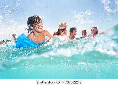 Group of happy kids play in the sea on matrass
