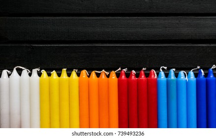 1 つの行と行、黒の背景、鮮やかな白のキャンドルで多くのカラフルなキャンドル。黄色、オレンジ、赤、青の色、虹のグラデーション