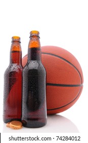 Dos botellas de cerveza abiertas y una pelota de baloncesto sobre un fondo blanco con reflejo. Formato vertical desde un ángulo bajo.