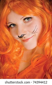 Una mujer joven con una peluca naranja y bigotes de tigre pintados juega un tigre