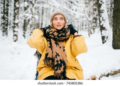 Extraña mujer bizarra tirada en un árbol en un bosque nevado de invierno. Hermosa joven encantadora relajante al aire libre. Mujer inusual de vacaciones descansando en la naturaleza. Mujer solitaria que viaja en un día de frío helado