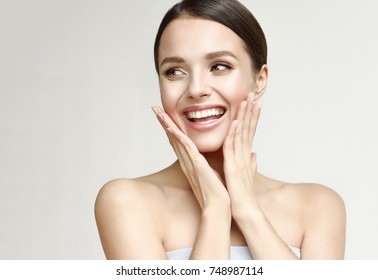 Feliz hermosa niña sosteniendo sus mejillas con una risa mirando hacia un lado. Mujer bonita piel limpia y fresca. Expresiones faciales expresivas. Cosmetología, belleza y Spa